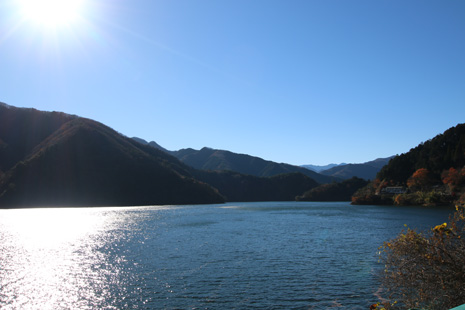 陽に照らされ、山の影を映し出す小河内ダムの水面