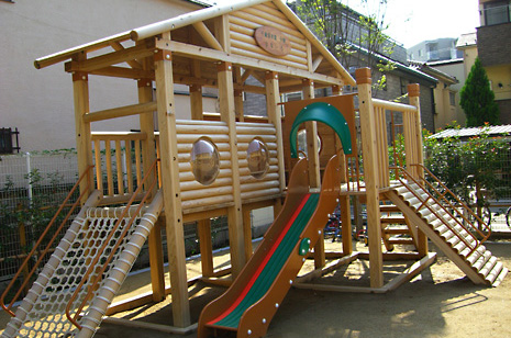 木を活かしたログハウスの様なデザインで、滑り台や縄のネットが取り付けられた遊具